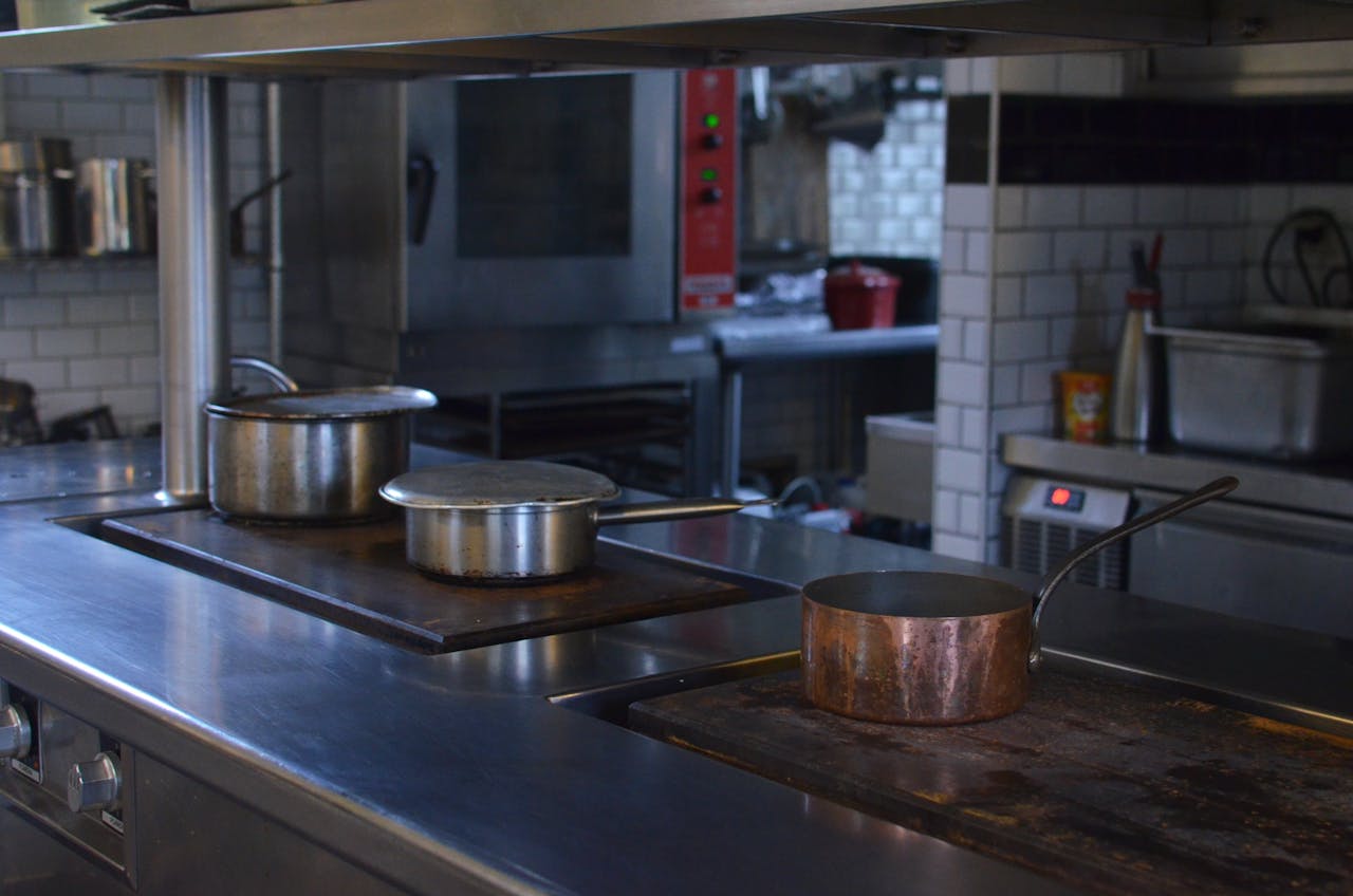 services-03 Stainless steel pots on a kitchen counter in a professional restaurant setting.