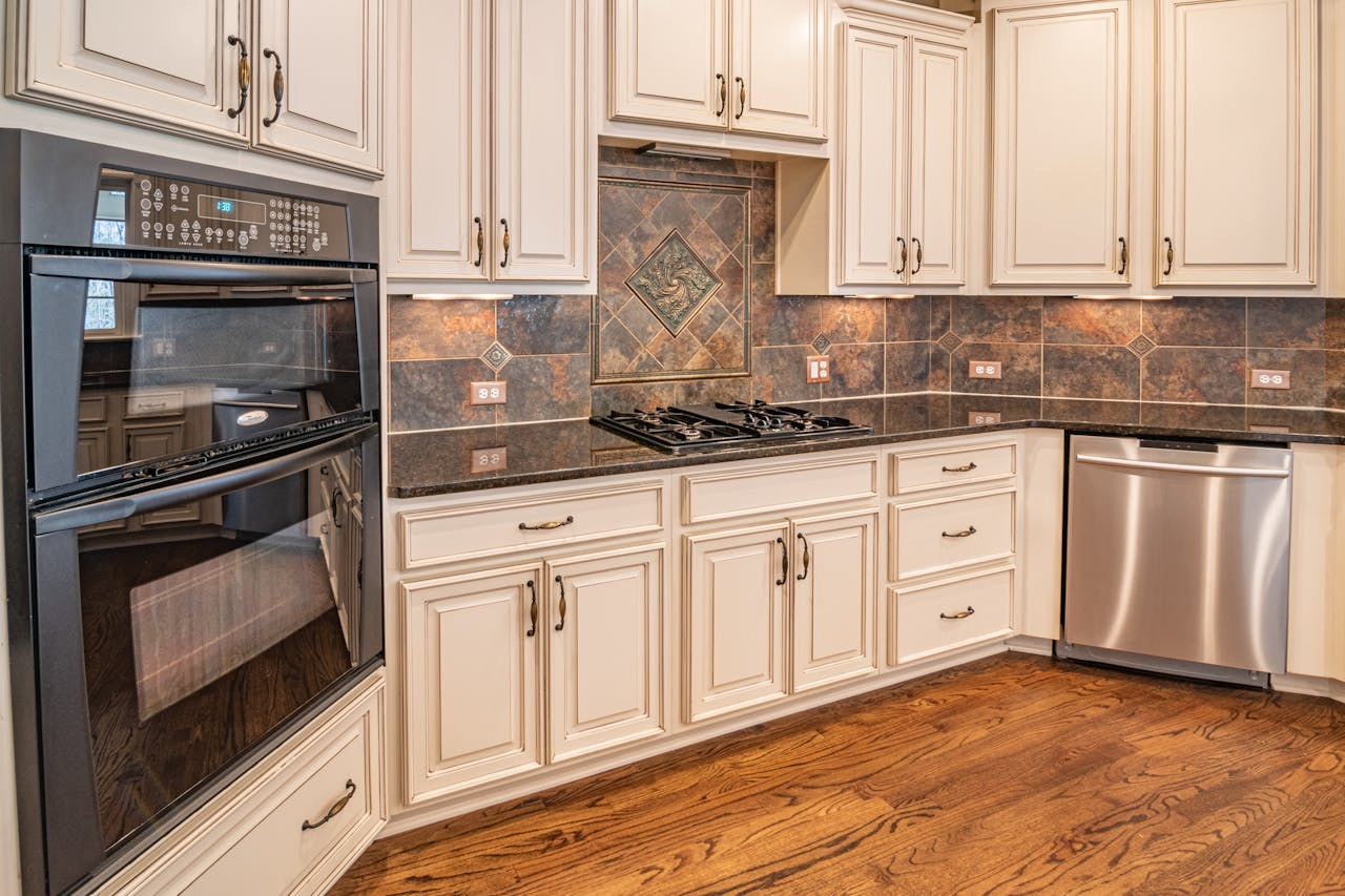 about-01 A modern kitchen featuring cabinets, a dishwasher, and a double oven with hardwood floors.